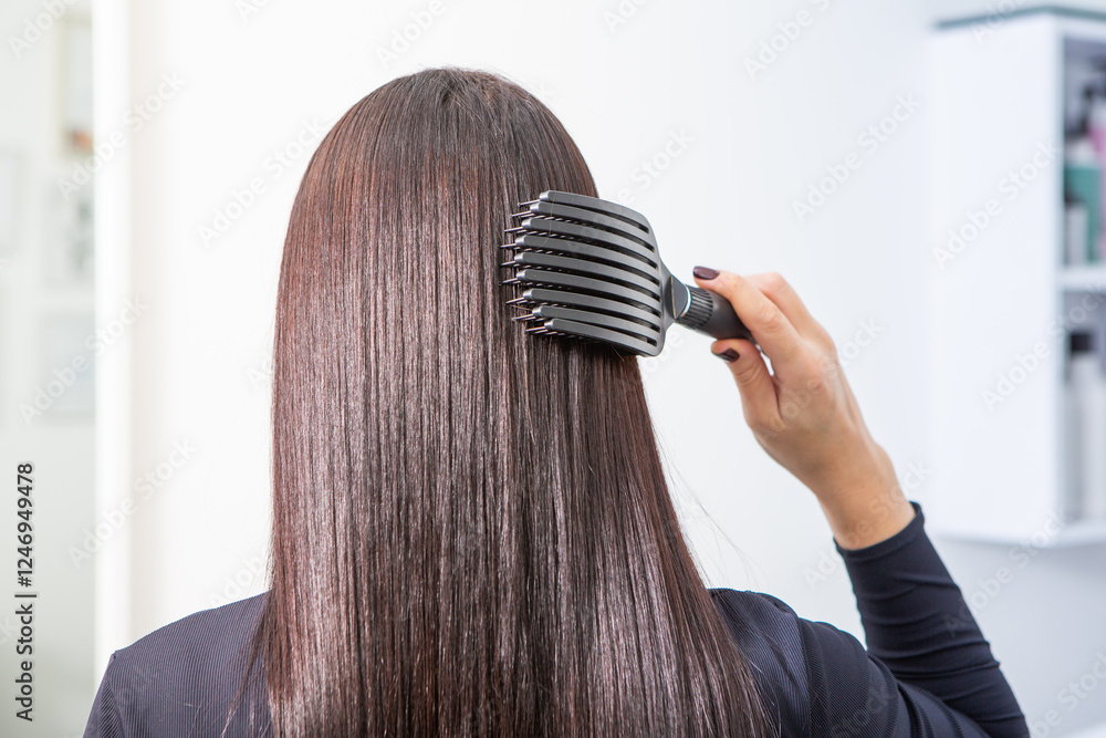 Fototapeta premium Elegant European Model Getting Hair Styled in Beauty Salon. Fashionable Woman Getting a Hairstyling Treatment at Salon. Healthy long hair