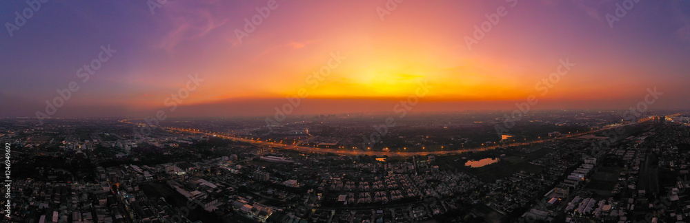 Obraz premium view of sunset city skyline, transportation with cars on Expressway, Road, Roundabout, multilevel junction highway-Top view. Important infrastructure, cloudscape, cityscape, building, crane.