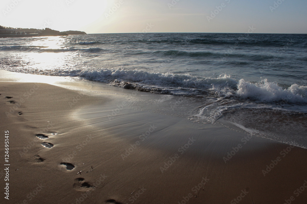 Beach of luxury hotel. sunny day, windy, stormy, wavy sea, blue sky. shines soft yellow-gold brown-golden sand with sunsets. Sea waves crashing on the shore with wavy white foam. on island of cyprus. 