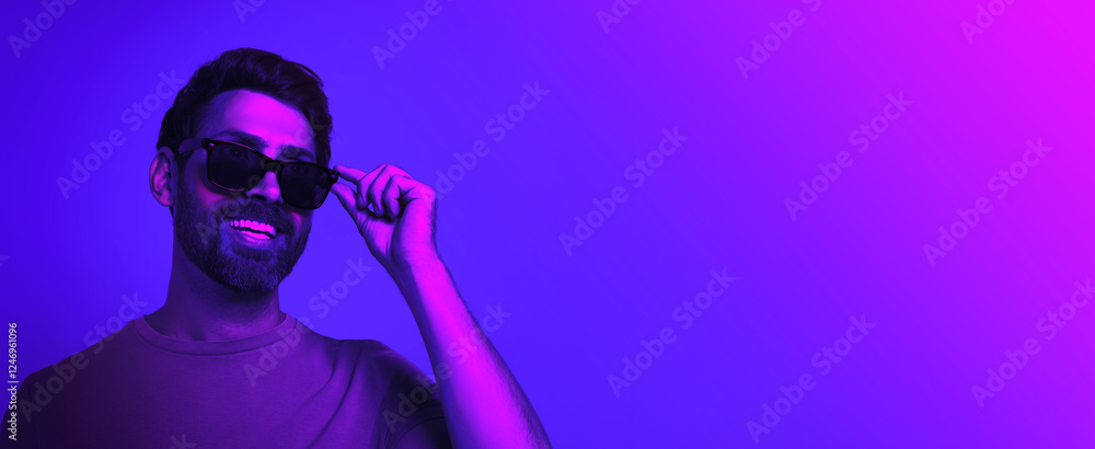 Bearded man with stylish sunglasses smiling in neon light, space for text. Banner design Bearded man with stylish sunglasses smiling in neon light, space for text. Banner design