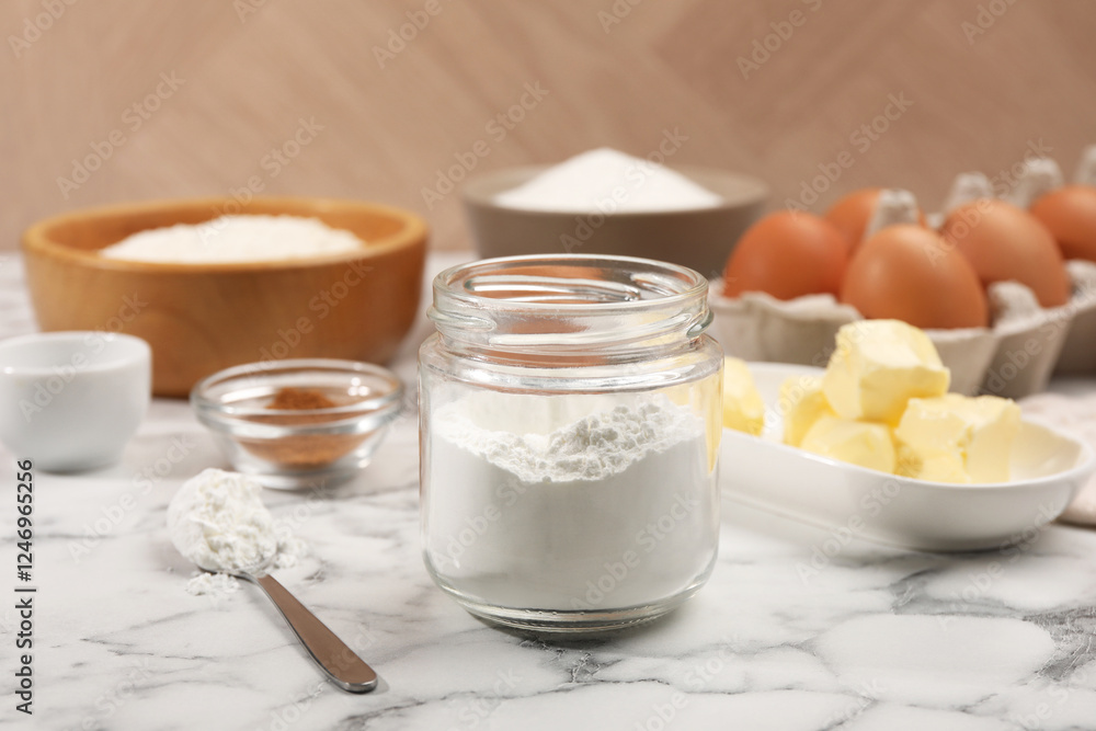 Baking powder in jar and other products on white marble table, closeup Baking powder in jar and other products on white marble table, closeup