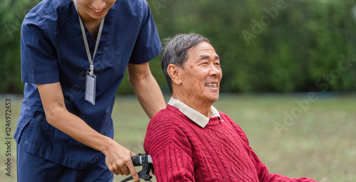 Papier peint Caregiver smiling while pushing elderly man in wheelchair through a beautiful ga