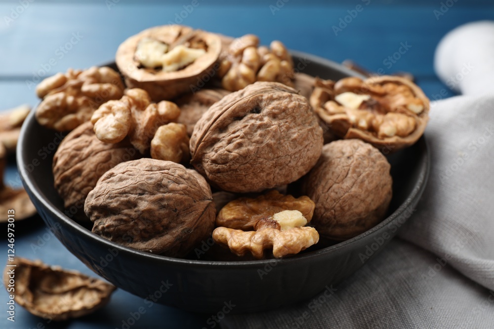 Fresh walnuts in bowl on blue table, closeup Fresh walnuts in bowl on blue table, closeup