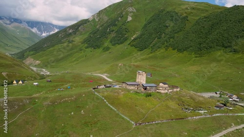 Lamaria Monastery Complex, standing among green meadows in historic village of Ushguli, with stone walls and tower in picturesque Svaneti region of Georgia Drone Footage. photo