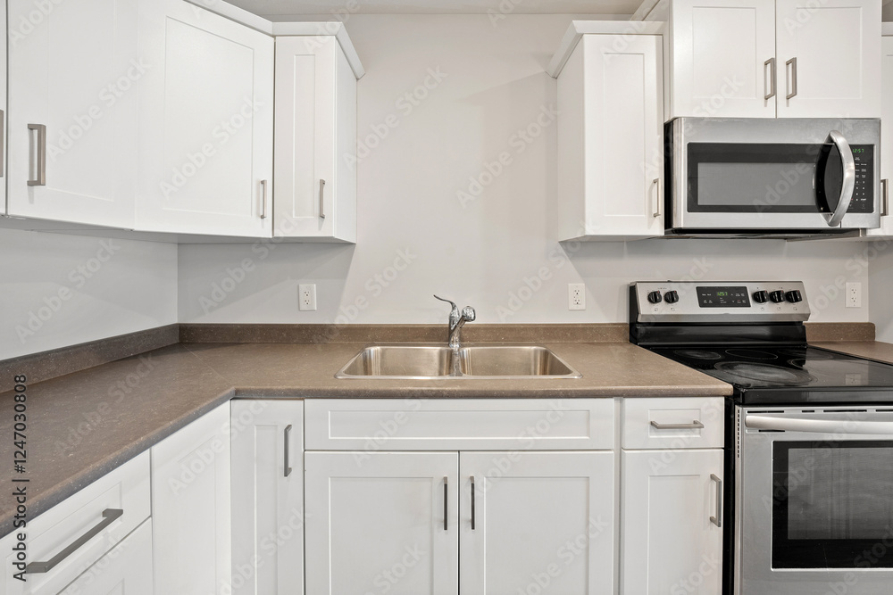 Fototapeta premium A clean and empty kitchen with a white stove and microwave