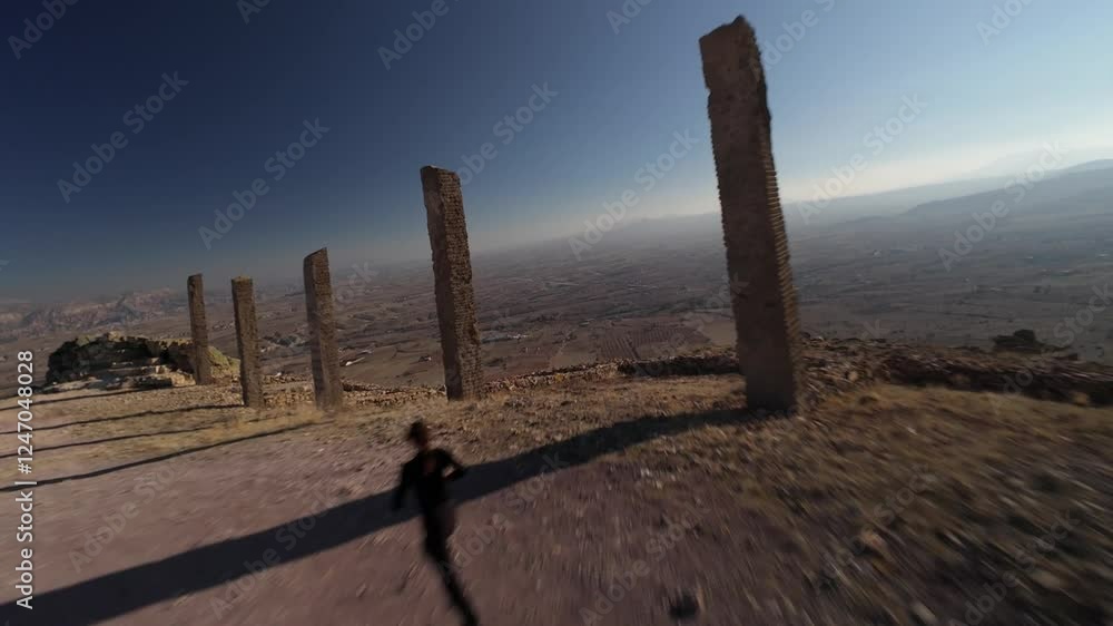 FPV Drone Flight Between the Columns of the A Day On Earth Sculpture in the Time and Space Sculpture Park with a Woman Running on the Path Between Them at Sunset FPV Drone Flight Between the Columns of the A Day On Earth Sculpture in the Time and Space Sculpture Park with a Woman Running on the Path Between Them at Sunset