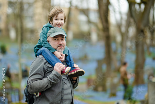 Papier peint Little boy and his father admiring blue scilla siberica spring flowers blossoming in April in Bernardine cemetery, one of the three oldest graveyards in Vilnius, Lithuania