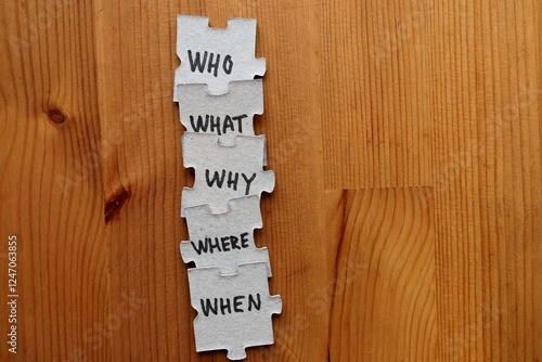 Who, what, why, where, when puzzle pieces. Questions that need answer concept. Wooden background.