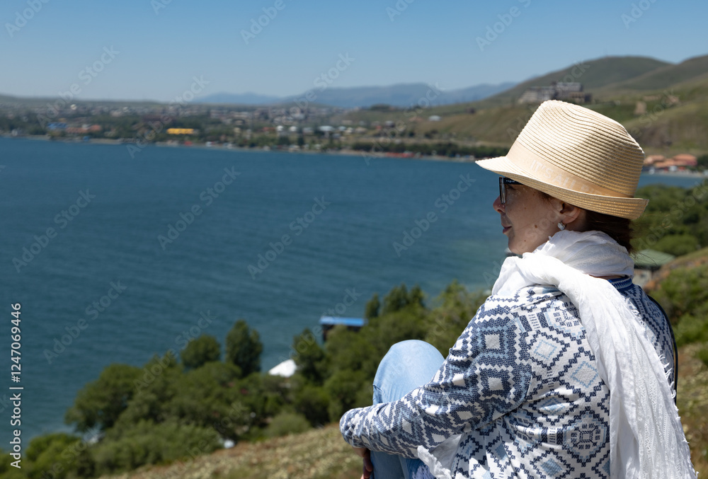 Fototapeta premium Enjoying a peaceful moment by the serene lake with mountains in the backdrop during a sunny day