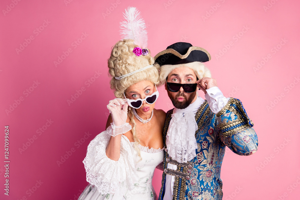 Costumed couple portraying historical nobility posing in front of a pink background with expressive gestures Costumed couple portraying historical nobility posing in front of a pink background with expressive gestures