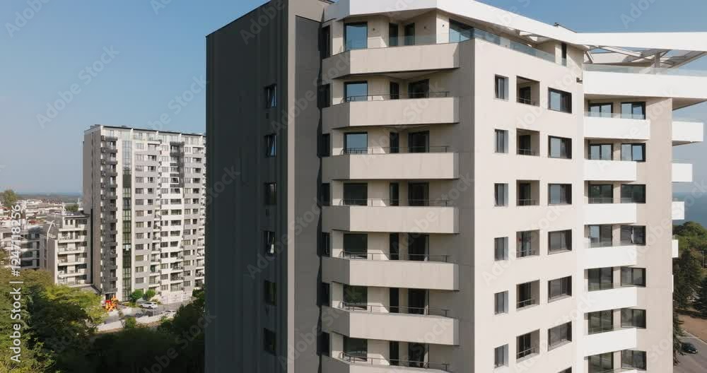 Stylish high-rise condominium with geometric balconies and large glass windows. Located aerial view, this residential complex blends luxury living with stunning sea and city views.