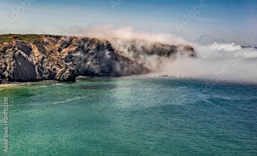 clouds covered cliffs on the beautiful beach of  Praia de Arrifana (Arrifana beach),Algarve, Portugal