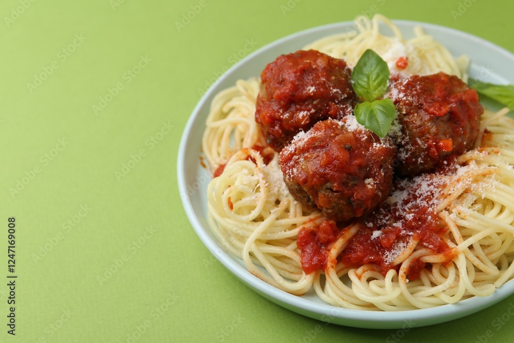 Delicious pasta with meatballs, basil and cheese on green table, closeup. Space for text Delicious pasta with meatballs, basil and cheese on green table, closeup. Space for text