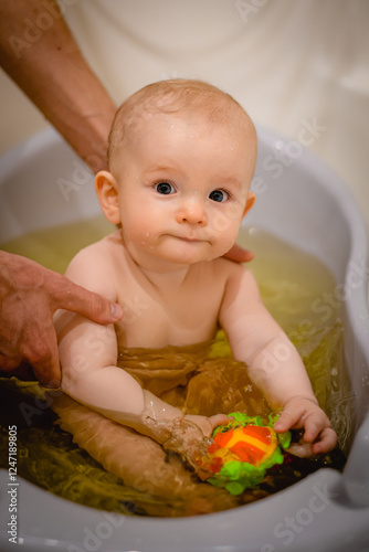 little boy toddler sitting in baby bathtub in water