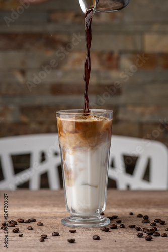 Obraz na płótnie Making iced latte in a tall glass with ice by adding coffee to milk w salonie