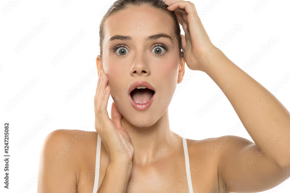 Shocked woman in white top, wide-eyed expression, hands on face, conveying surprise and dramatic emotion Shocked woman in white top, wide-eyed expression, hands on face, conveying surprise and dramatic emotion