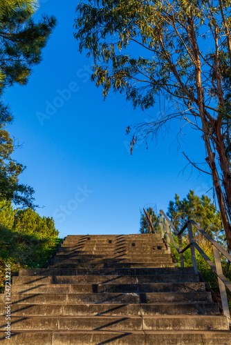 A sunlit stone staircase ascends toward a vibrant blue sky, fram