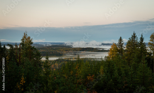 Morning mist over autumn forested valley with distant lakes and rolling hills under soft pastel sky photo