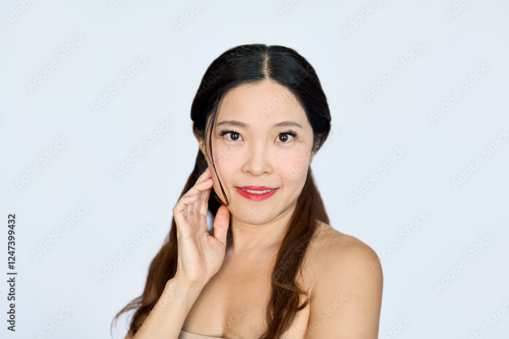Confident smiling mid aged Asian woman model advertising antiage face skin care beauty lifting rejuvenating facial treatment and cosmetics looking at camera isolated on white background. Portrait Confident smiling mid aged Asian woman model advertising antiage face skin care beauty lifting rejuvenating facial treatment and cosmetics looking at camera isolated on white background. Portrait