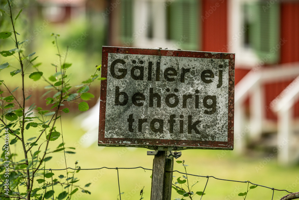 Obraz premium weathered swedish traffic sign on wooden post in rural area.