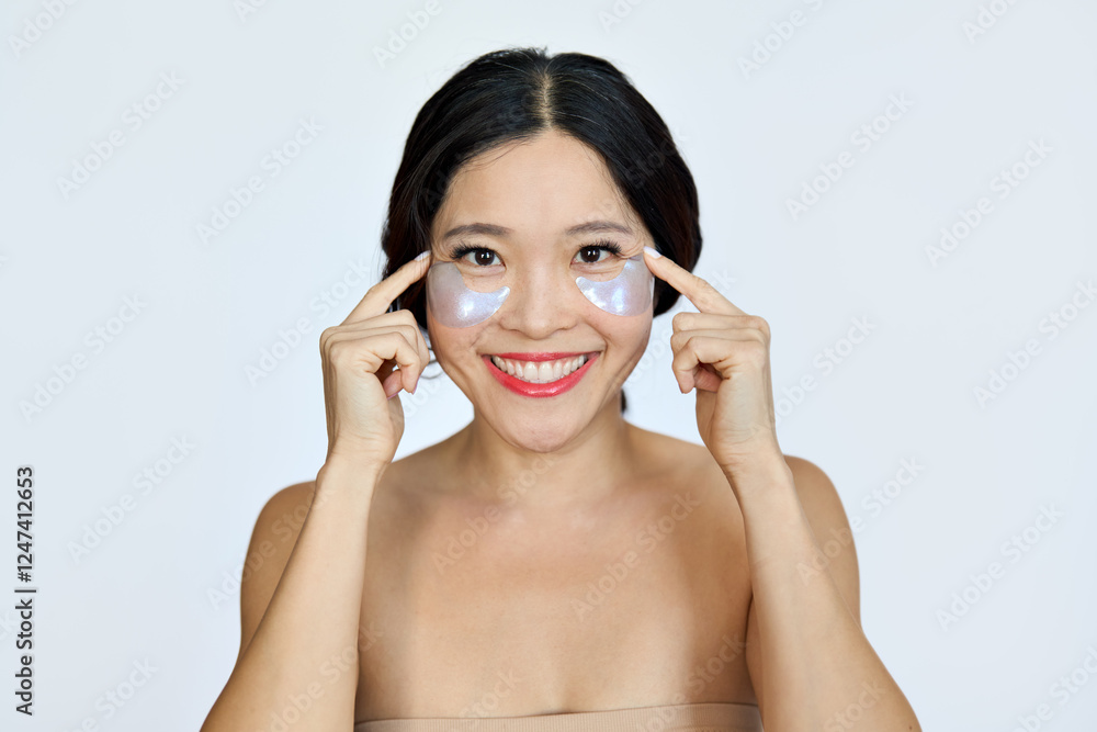 Happy smiling mature Asian woman model advertising antiage face skin care undereye hydrogel patches cosmetic treatment to reduce puffiness under eyes looking at camera isolated on white background. Happy smiling mature Asian woman model advertising antiage face skin care undereye hydrogel patches cosmetic treatment to reduce puffiness under eyes looking at camera isolated on white background.
