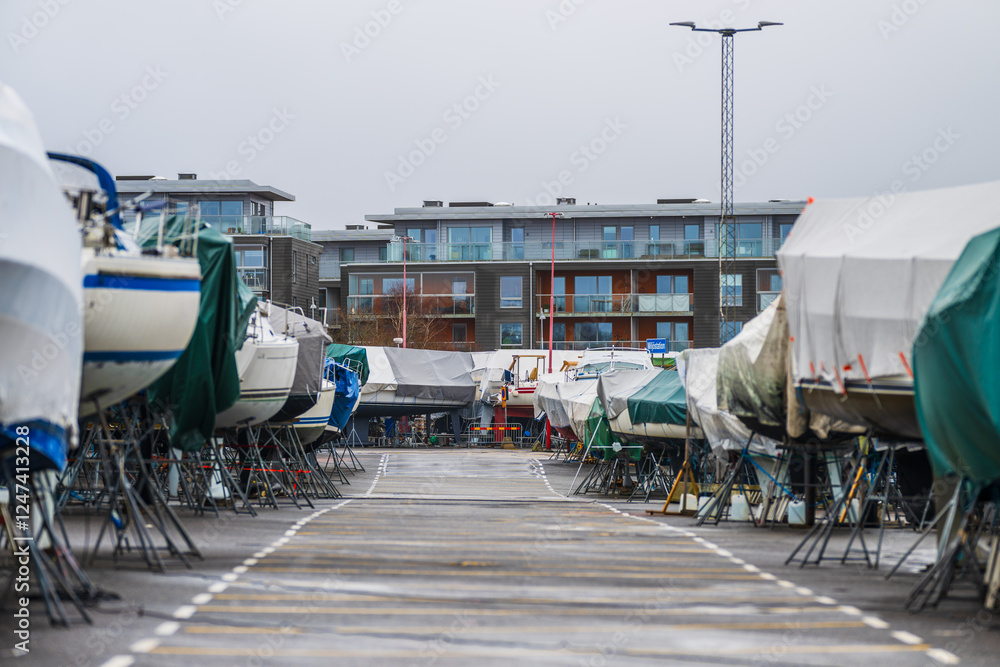 covered boats on metal stands in marina or boatyard on overcast day. covered boats on metal stands in marina or boatyard on overcast day.