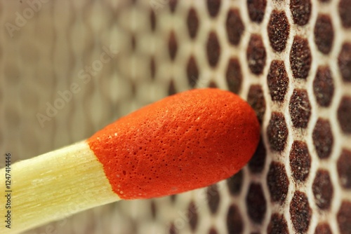 red tip of a match on the friction surface of a matchbox, detailed macro photo