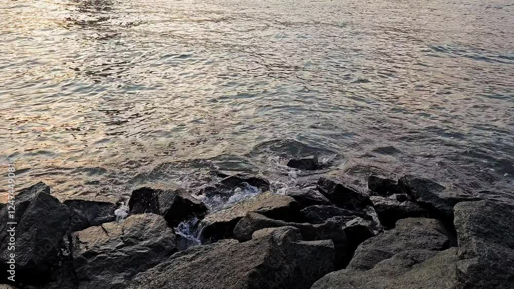 Rocky riverbank with calm rippling water at sunset, Close-up of rocks on a riverbank with gentle water reflections Rocky riverbank with calm rippling water at sunset, Close-up of rocks on a riverbank with gentle water reflections