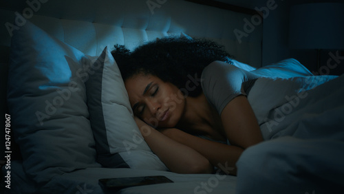 Beautiful African american girl sleeping in bed at home waking up turn off triggered alarm clock mobile phone message annoyed angry ethnic woman awake at night disturbed with incoming smartphone call photo