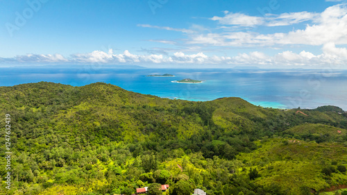 Wallpaper Mural A scenic view of rolling green hills extending towards a calm turquoise sea under blue sky. Praslin, Seychelles. Torontodigital.ca