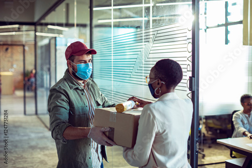 Delivery man handing package to office worker in modern workspace photo