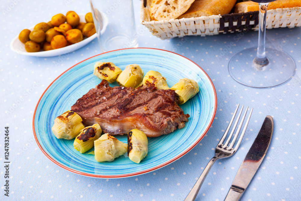 Delicious veal steak with fried artichokes on a blue plate Delicious veal steak with fried artichokes on a blue plate