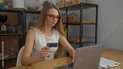 Woman holding credit card in office setting with laptop suggests online shopping scene enhancing modern professional lifestyle concept in indoor workplace environment.