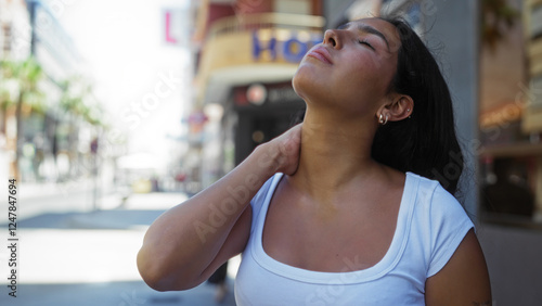 Wallpaper Mural Young woman relaxing outdoors in an urban city street, enjoying the sunny day with a calm and content expression Torontodigital.ca