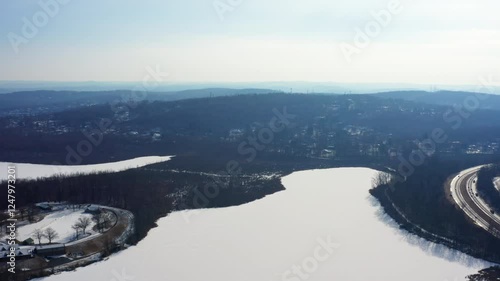 Wallpaper Mural Aerial drone shot flying right over the frozen Mohansic Lake in FDR Park, Yorktown Heights, NY. The Taconic State Parkway curves alongside the snowy terrain with a vast winter horizon. Torontodigital.ca
