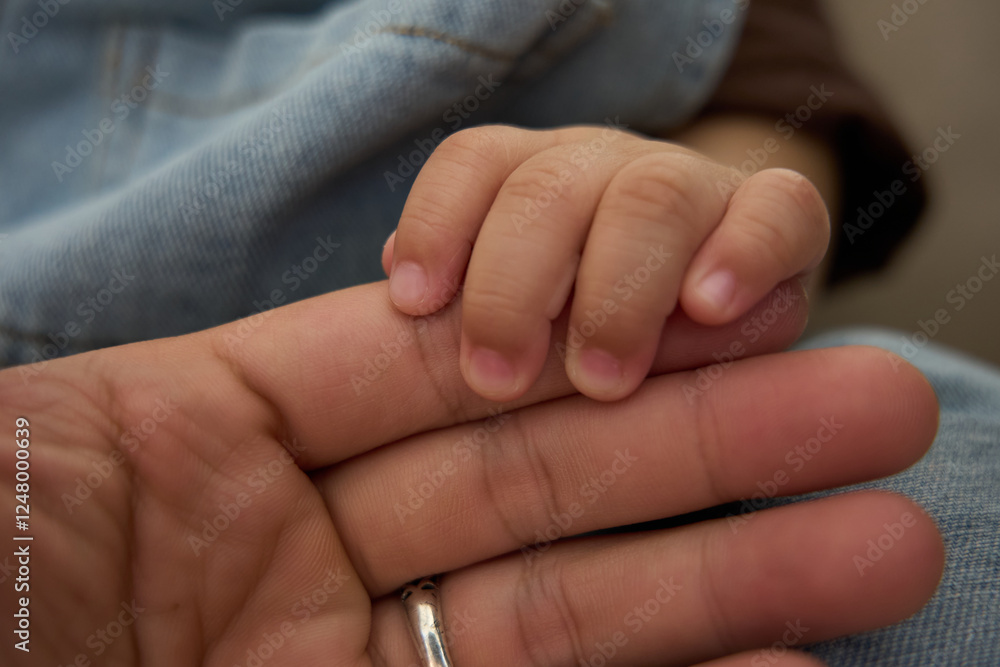 someone holding a baby ' s hand with a ring on it someone holding a baby ' s hand with a ring on it