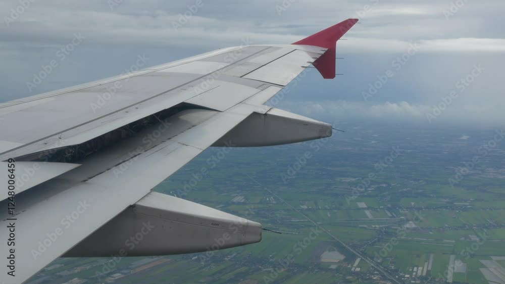 view through aircraft window with plane's wing over green farm field site suburb of Bangkok area while plane is landing view through aircraft window with plane's wing over green farm field site suburb of Bangkok area while plane is landing