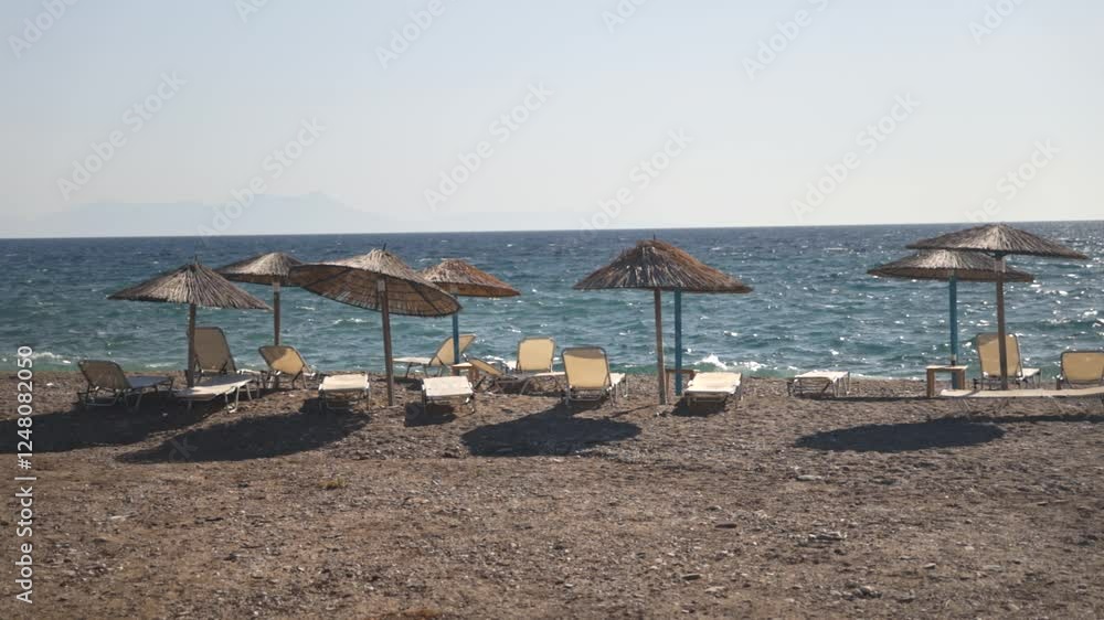 A serene beach with straw umbrellas lined up along the shore. A serene beach with straw umbrellas lined up along the shore.