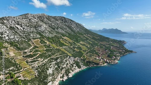Backward aerial view of Peljesac Peninsula’s rugged coastline, vineyards, and Adriatic Sea, Croatia
