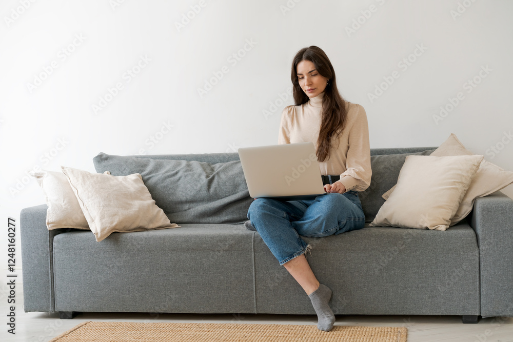 Woman is sitting on a couch with a laptop in front of her Woman is sitting on a couch with a laptop in front of her