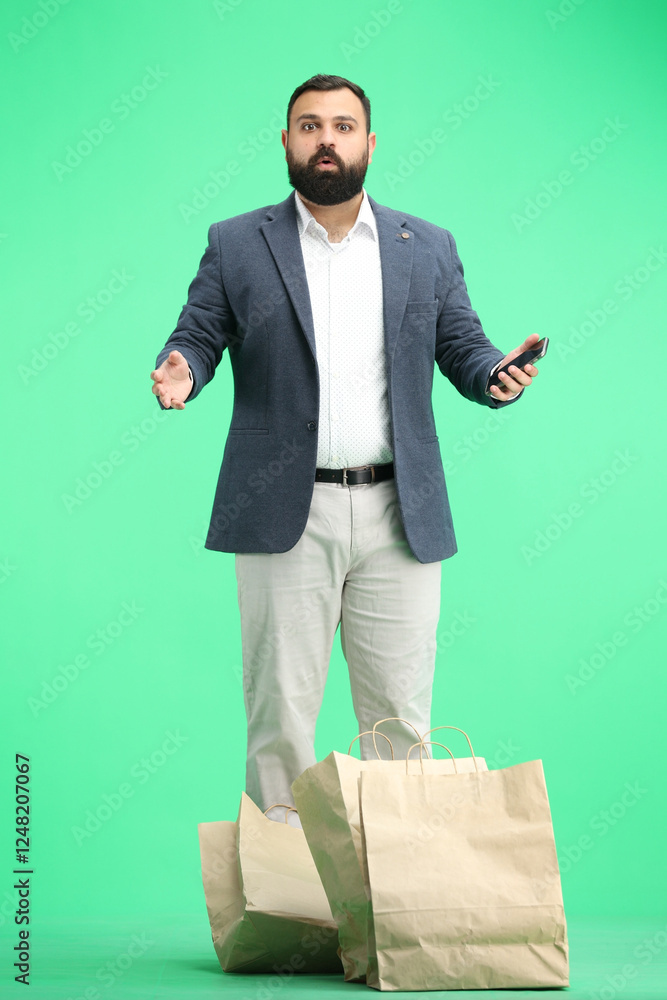 A man, full-length, on a green background, with a phone A man, full-length, on a green background, with a phone