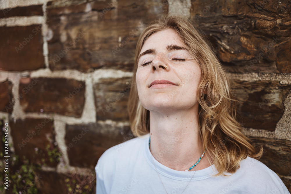 Woman Relaxing with Eyes Closed Against a Brick Wall Woman Relaxing with Eyes Closed Against a Brick Wall