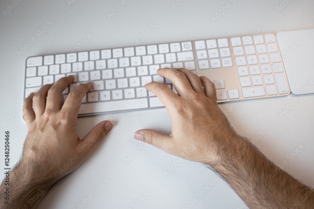 Male hands typing on wireless keyboard on white desk Male hands typing on wireless keyboard on white desk