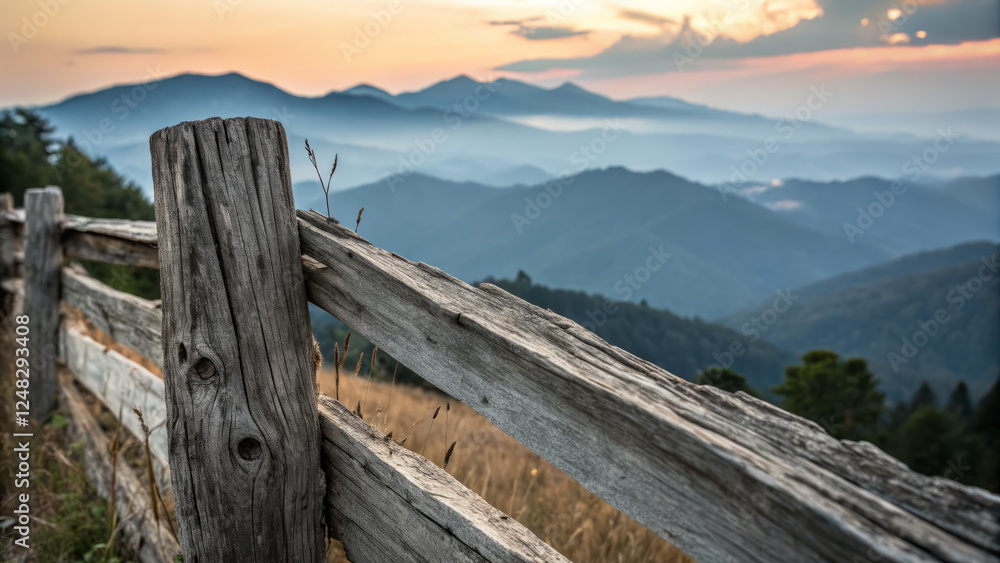 Fototapeta premium Rustic wooden fence overlooking serene mountain landscape at sunset