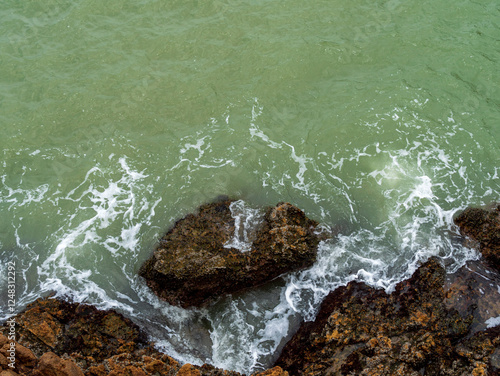 Obraz na plátně Waves lapping at the rocks along the shore