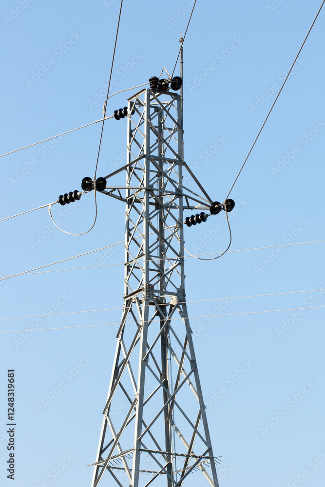 A galvanized steel power transmission tower standing tall against the backdrop of a clear blue sky, efficiently conducting electricity across vast distances A galvanized steel power transmission tower standing tall against the backdrop of a clear blue sky, efficiently conducting electricity across vast distances
