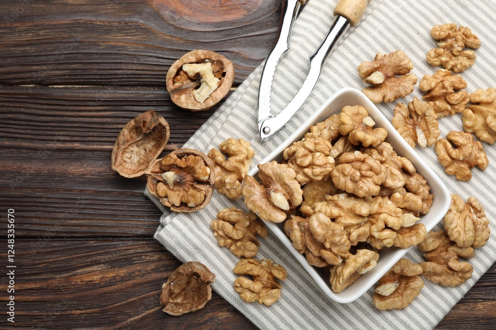 Peeled walnuts in bowl and nutcracker on wooden table, flat lay Peeled walnuts in bowl and nutcracker on wooden table, flat lay