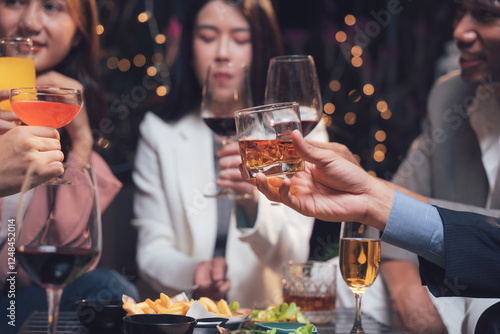 Fotografija Cheers to Connection: Friends raise their glasses in a celebratory toast, surrounded by the warm ambiance of a lively gathering
