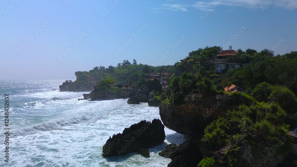 Aerial Drone view of the beach with white sand, coral rocks, hills with trees, waves from the ocean which is a tourist destination known as Mesra Beach Gunung Kidul Yogyakarta Aerial Drone view of the beach with white sand, coral rocks, hills with trees, waves from the ocean which is a tourist destination known as Mesra Beach Gunung Kidul Yogyakarta