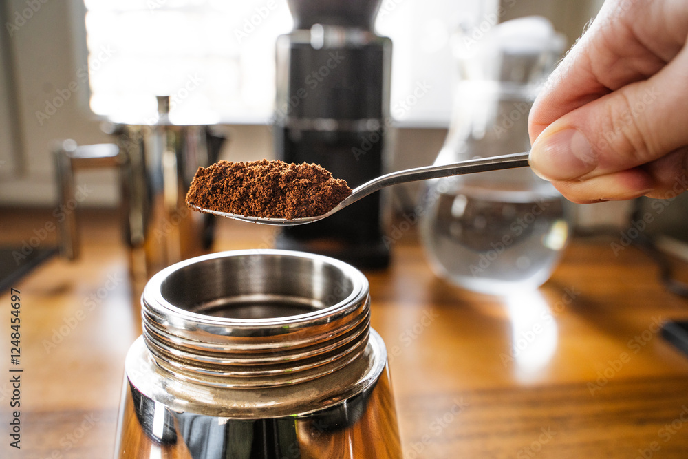 The process of making coffee with a stainless steel geyser moka pot. Person preparing coffee using a moka machine in a home kitchen. Close-up side view. The process of making coffee with a stainless steel geyser moka pot. Person preparing coffee using a moka machine in a home kitchen. Close-up side view.